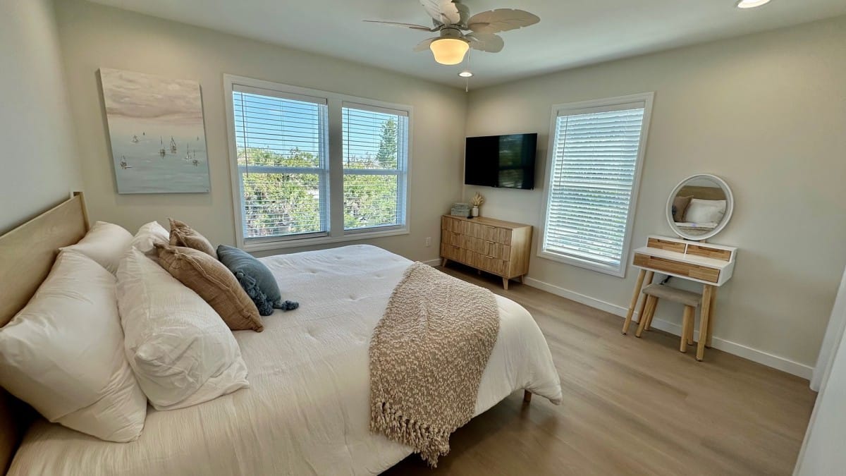 King bedroom with neutral bedding and bedside lamps